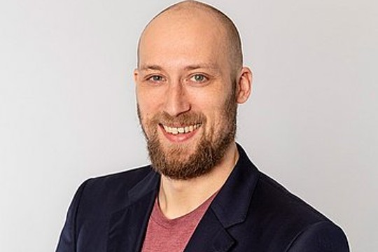 Lächelnder Mann mit dunklem Sakko. 