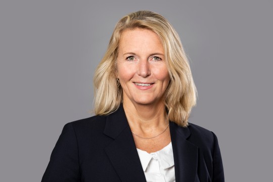 Lächelnde Frau vor einem grauen Hintergrund. 