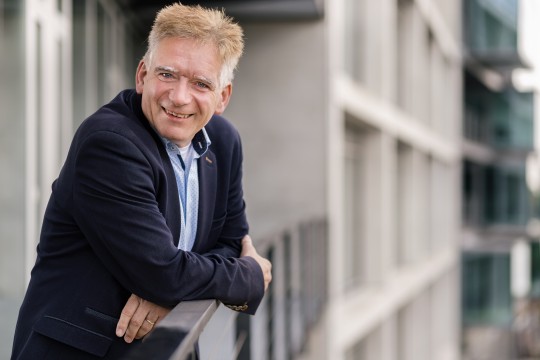 Lächelnder Mann mit verschränkten Armen. 