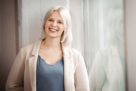 Lächelnde Frau vor einem hellen Hintergrund. 